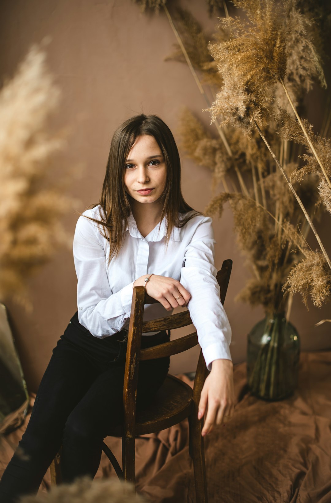 woman in white long sleeve shirt sitting on brown wooden chair