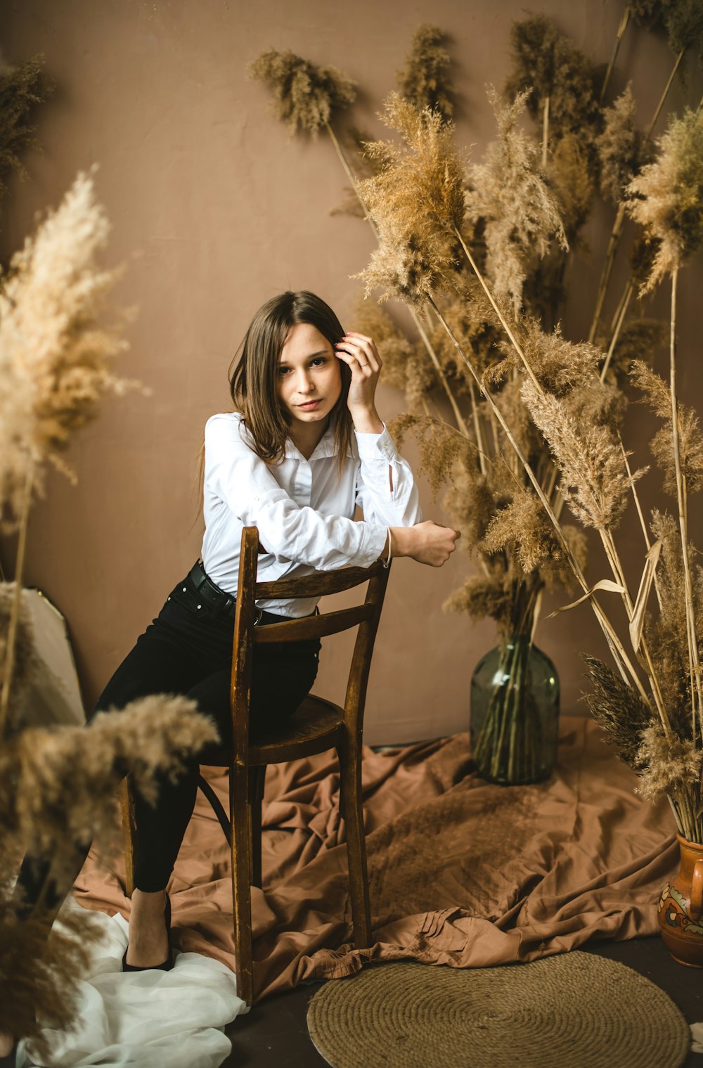 woman in white long sleeve shirt sitting on brown wooden chair