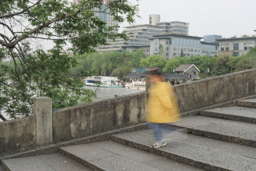 man in yellow shirt standing on gray concrete pavement during daytime