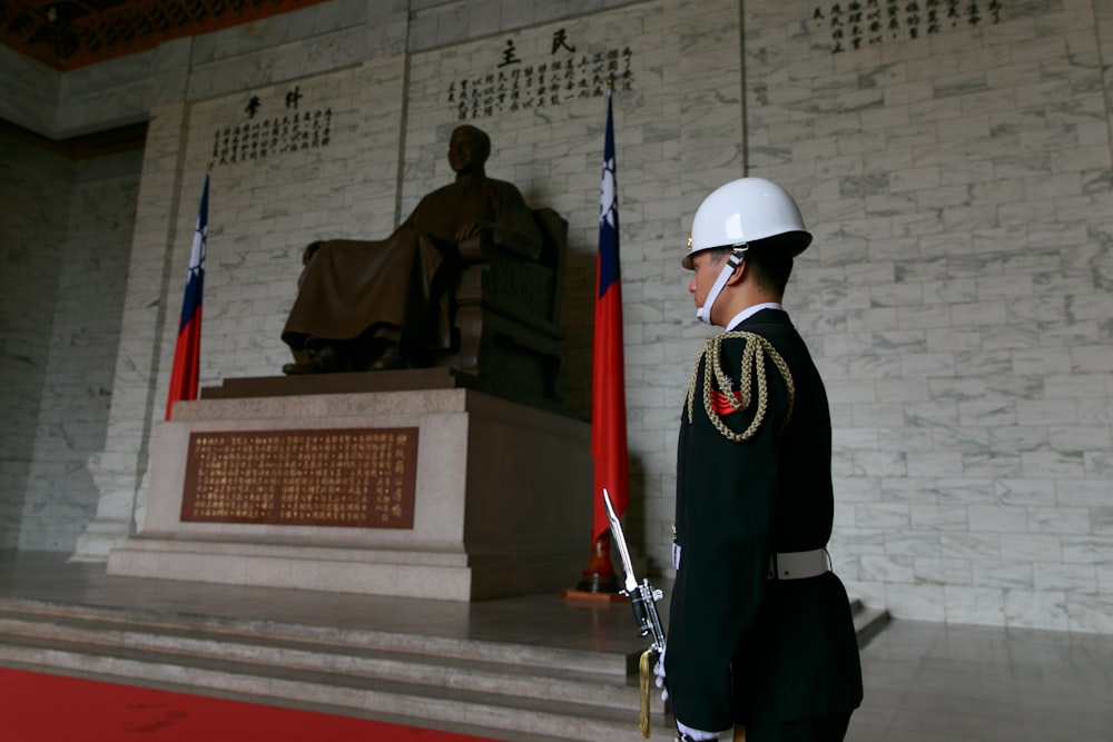 homme en uniforme noir et blanc tenant un fusil rouge et noir