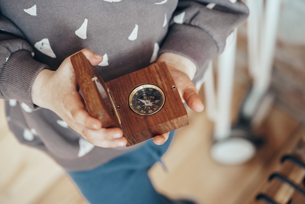 person in gray and white star print long sleeve shirt holding brown wooden box