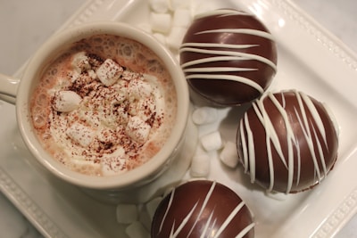 A steaming cup of rich hot chocolate topped with whipped cream and a sprinkle of cocoa powder, set against a cozy backdrop.