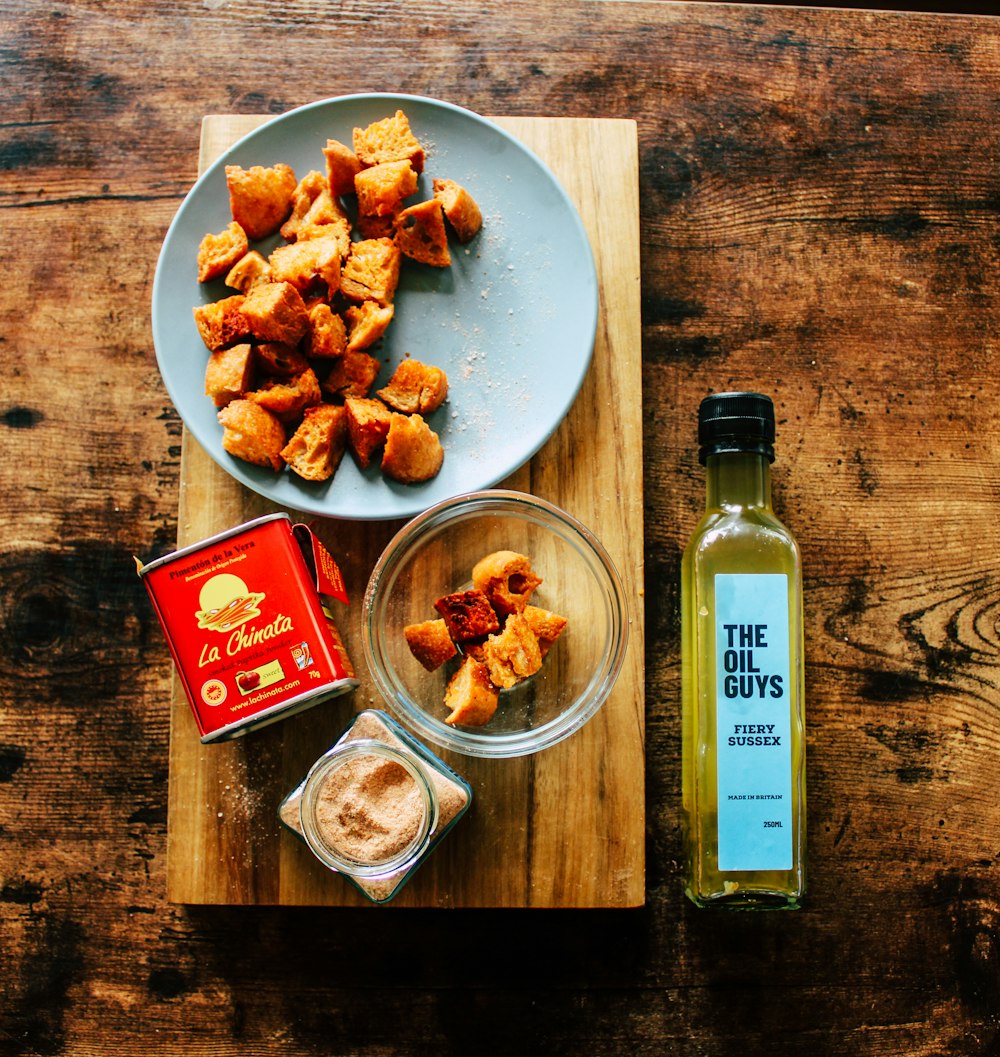 clear glass bottle beside white ceramic bowl with food on brown wooden table