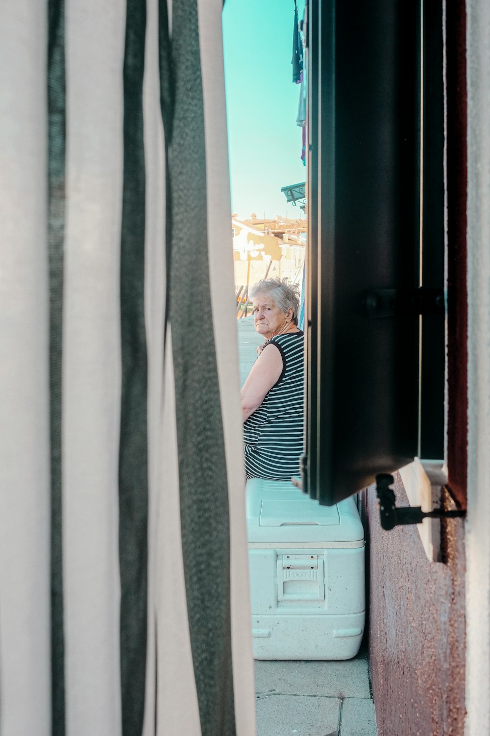 woman in black and white stripe dress standing beside window