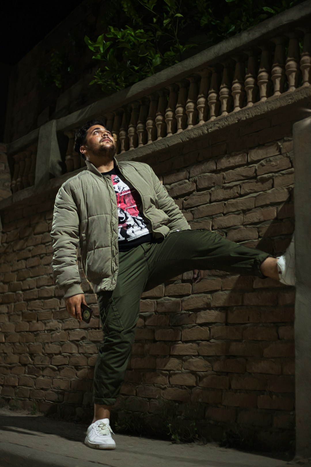 man in gray jacket standing beside brick wall