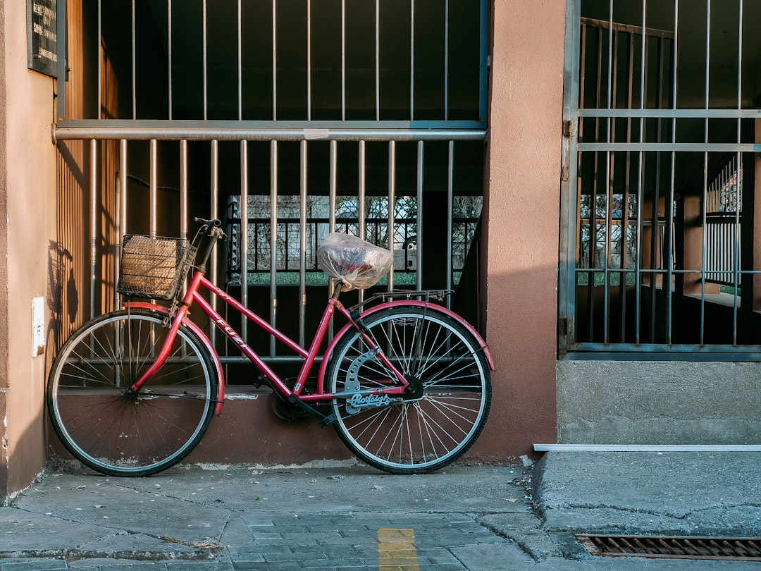 red city bike beside brown brick wall