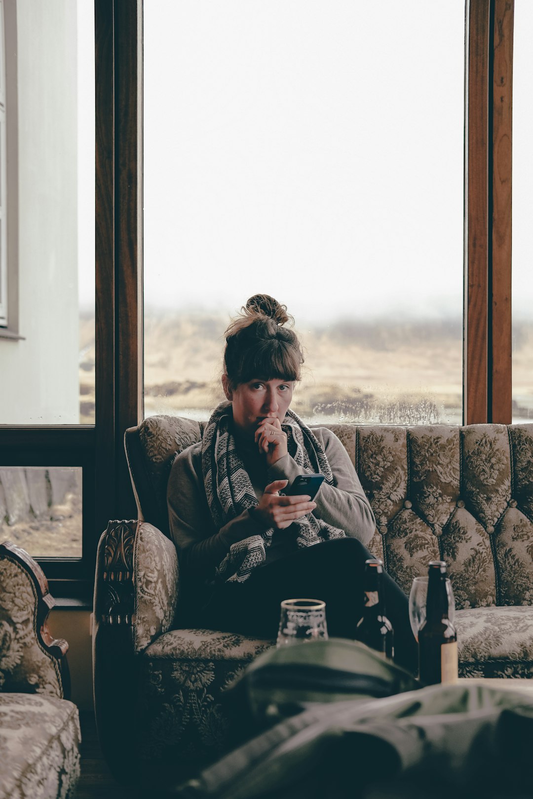 man in brown and black coat sitting on brown and white floral sofa chair