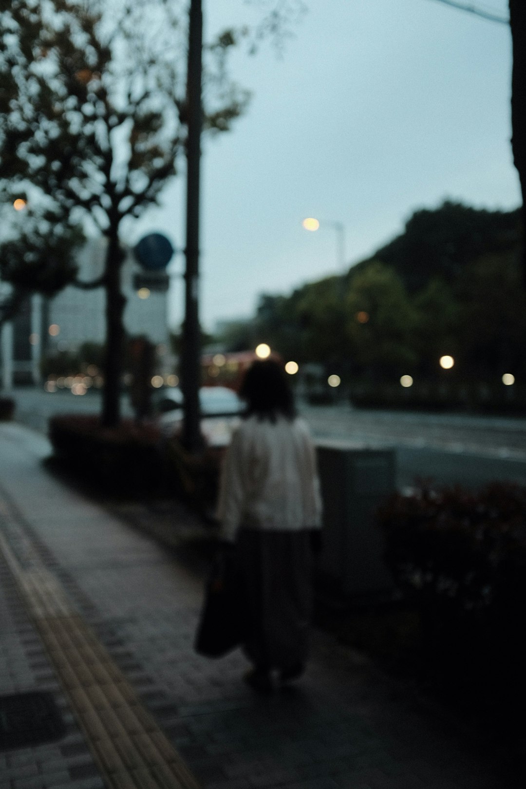 woman in white coat standing on sidewalk during night time