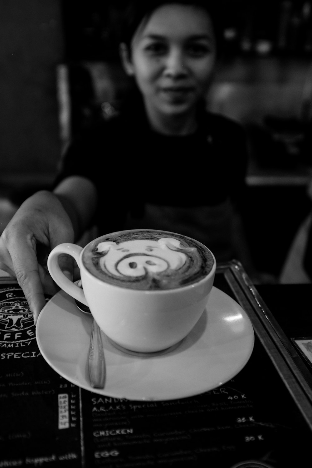 コーヒーとセラミックマグカップを持っている人のグレースケール写真