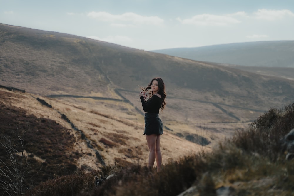 woman in black jacket standing on brown grass field during daytime