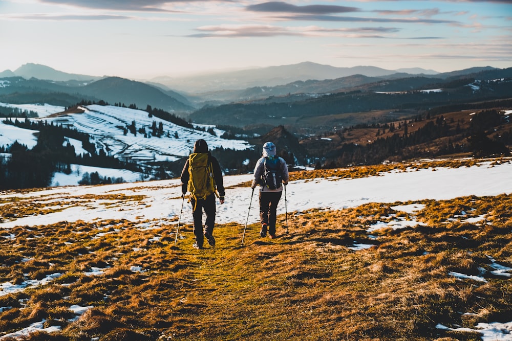 2 men walking on snow covered ground during daytime