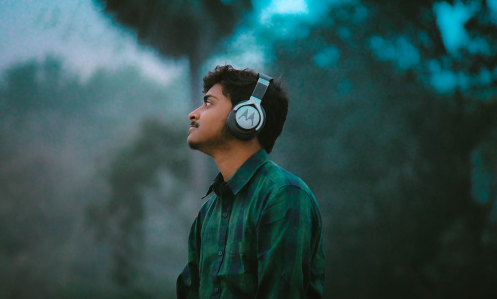 man in green and black plaid dress shirt wearing black and white headphones