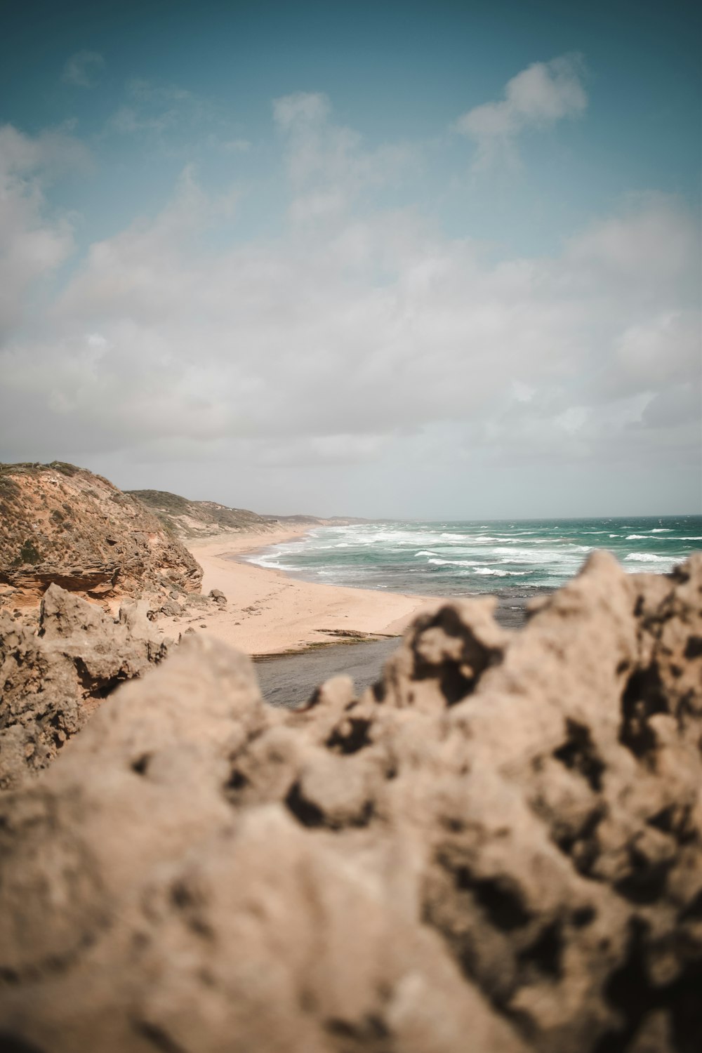 brown rocky shore near body of water under white cloudy sky during daytime