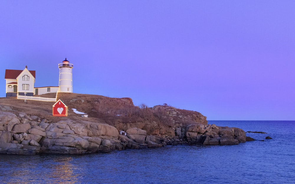 white and brown lighthouse on brown rock formation near body of water during daytime