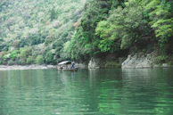 Travelers enjoying a peaceful boat ride on a calm river surrounded by dense forest.