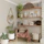 A cozy living room corner featuring a wooden bench stool and a woven decorative basket filled with blankets.