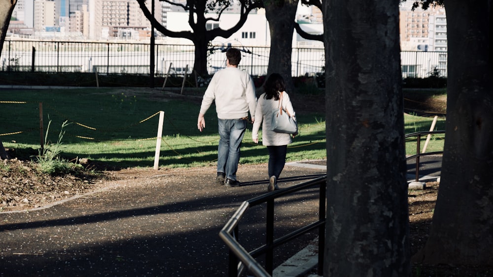 man in white dress shirt and blue denim jeans standing beside woman in white long sleeve