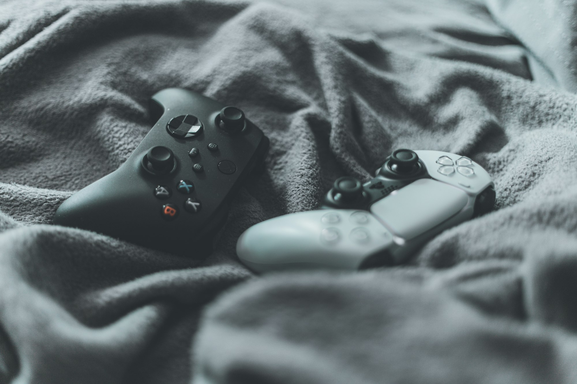Ein Xbox Series X Controller und der PlayStation 5 DualSense Controller auf einer Decke