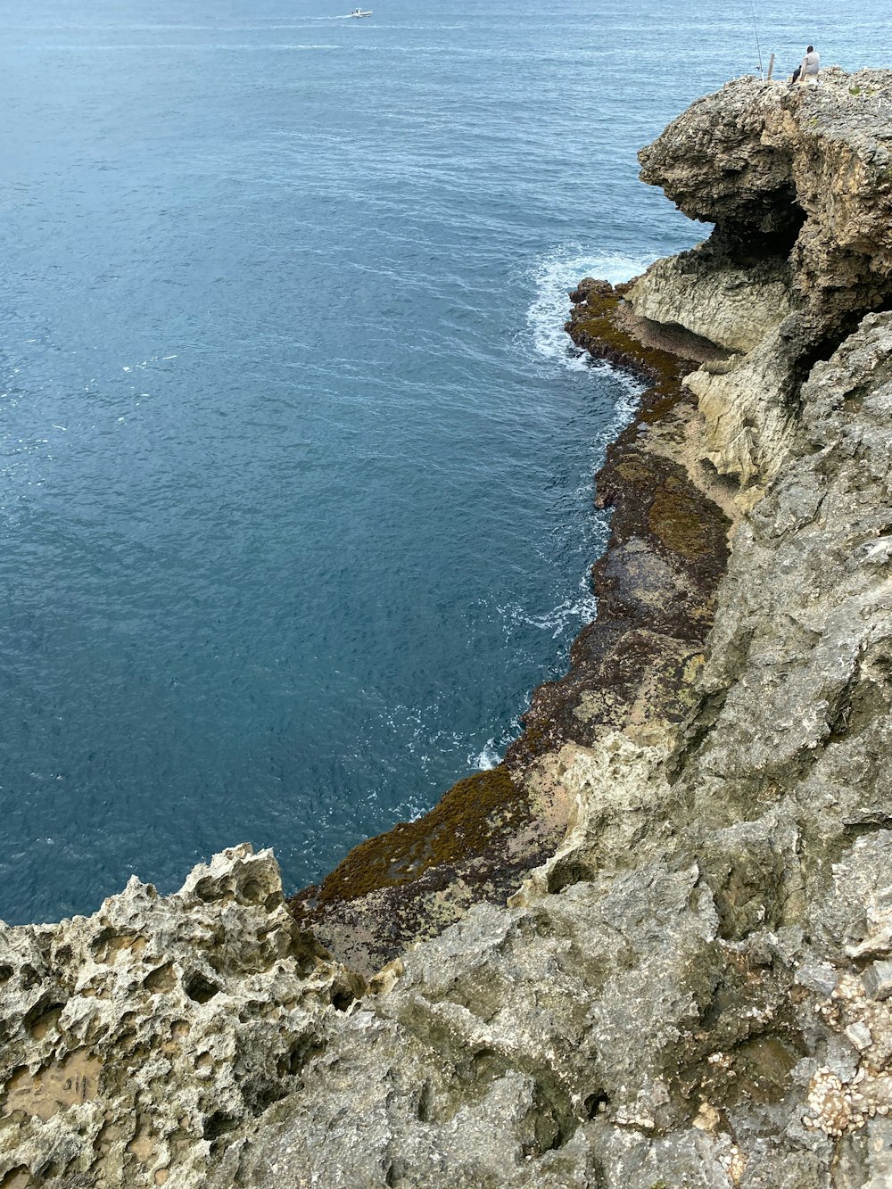 brown rocky mountain beside blue sea during daytime