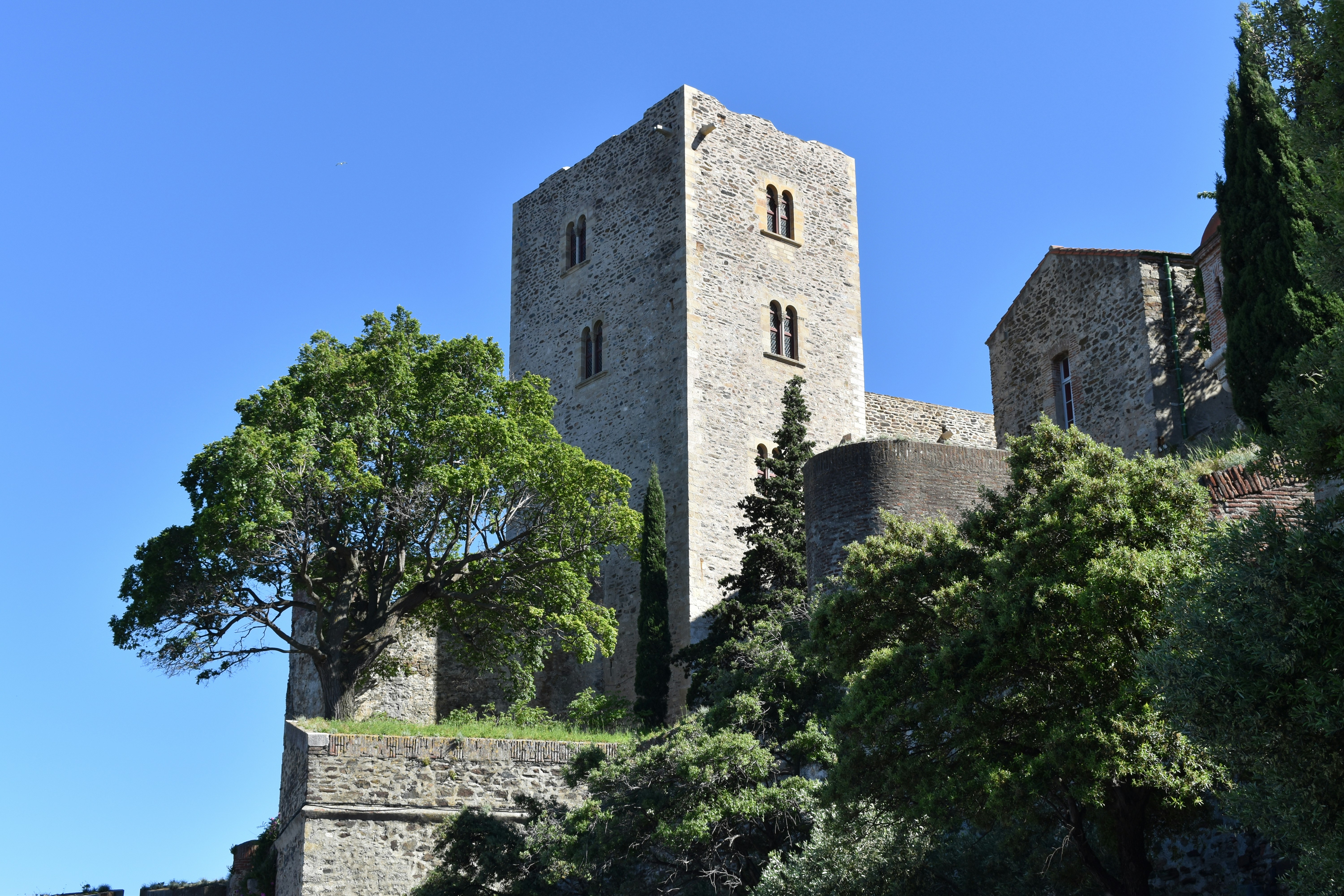brown concrete building near green trees under blue sky during daytime