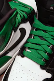 Side profile of a racing shoe featuring bold green detailing.