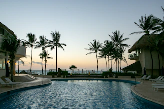 A serene private villa poolside with lush tropical gardens at dusk.