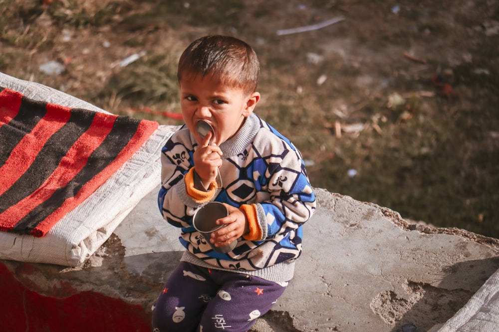 boy in blue and white sweater holding white and red textile