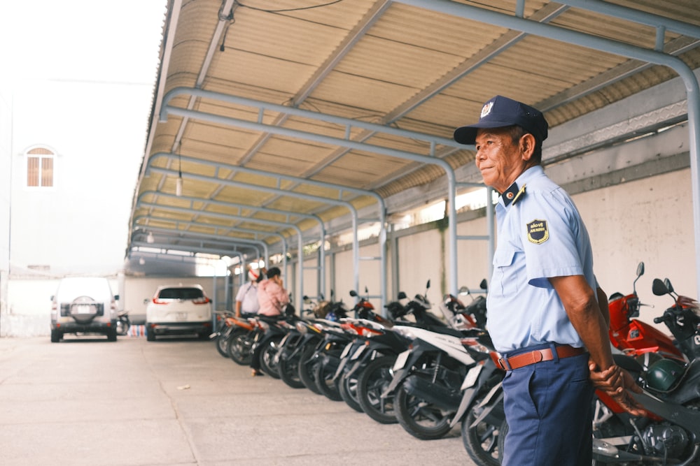 man in white long sleeve shirt and black hat standing beside motorcycle