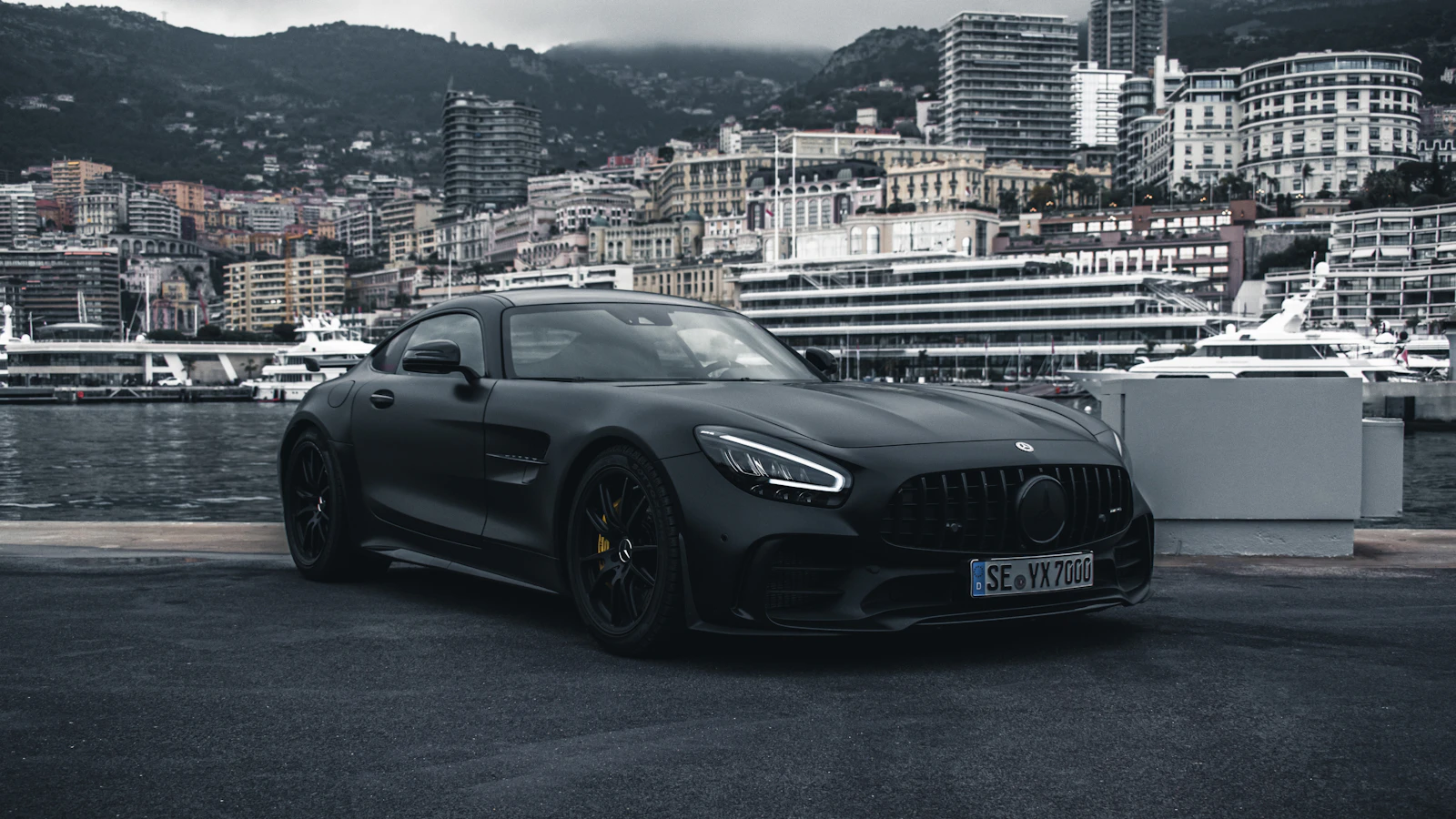 Matte black Mercedes-AMG GT sports car parked on a harbour quay at dusk