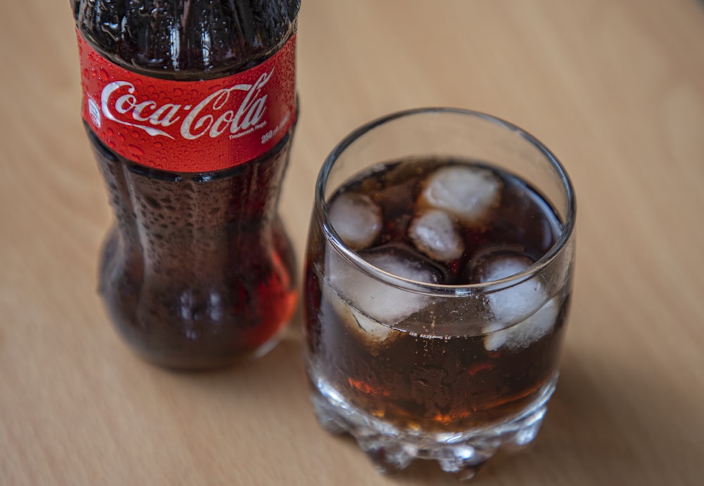 Bouteille de Coca Cola à côté d’un verre à boire transparent