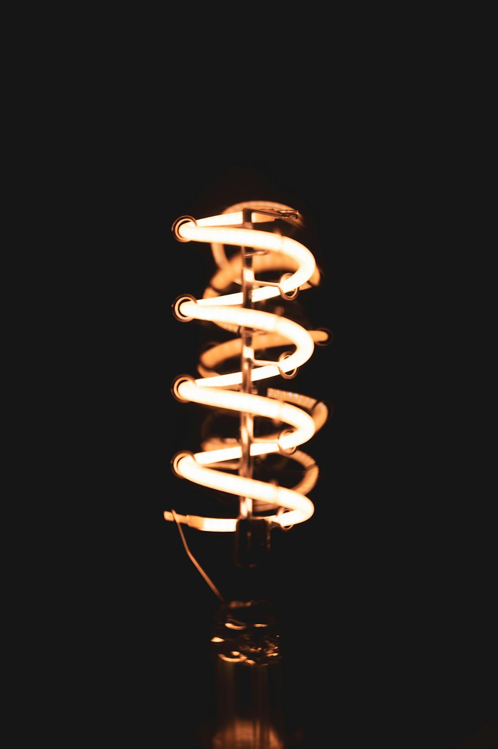 white spiral light bulb turned on in dark room