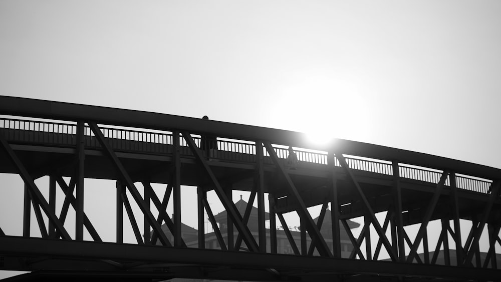 grayscale photo of bridge under cloudy sky