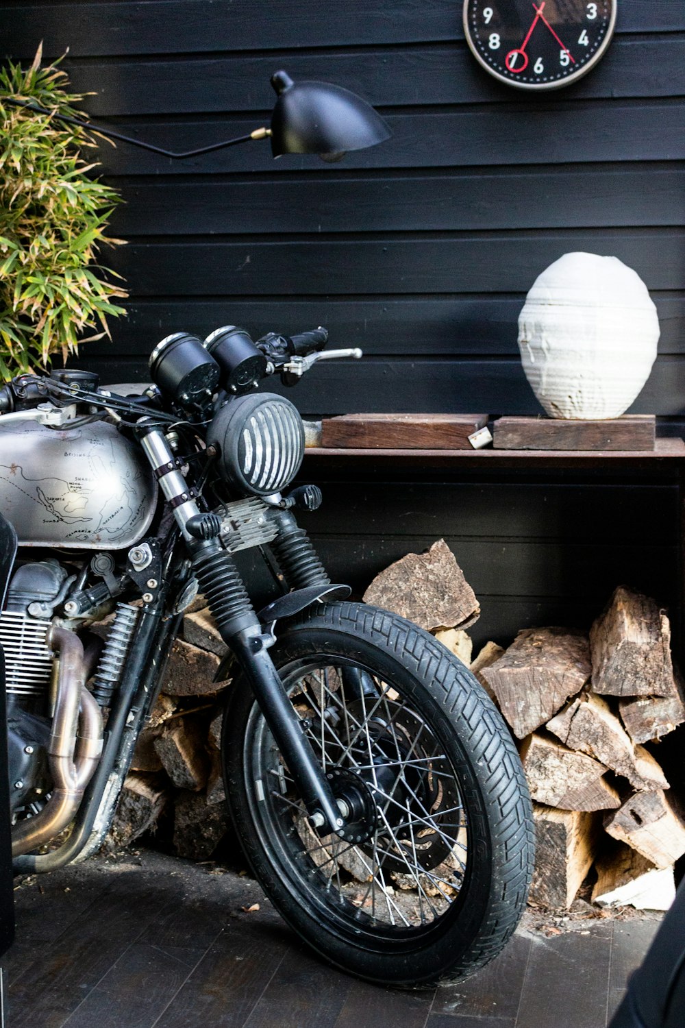 black motorcycle parked beside gray wooden wall