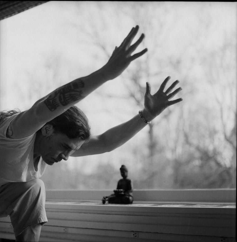 grayscale photo of woman in crew neck t-shirt raising her hands