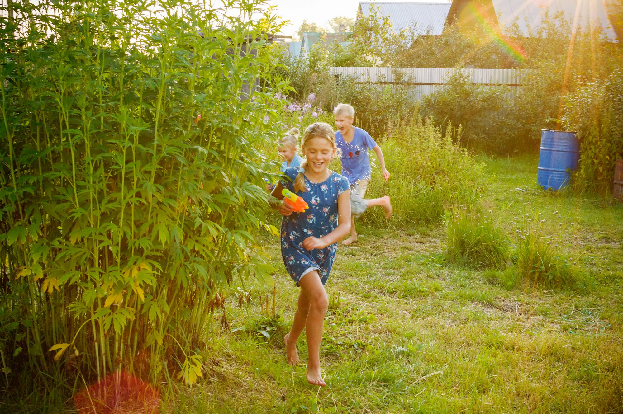 A group of kids playing with water guns outside, they run and cheer