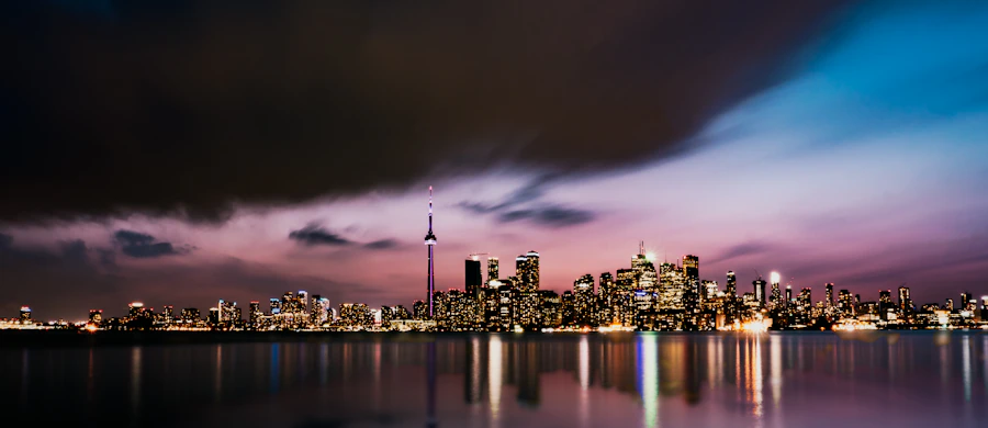 Toronto skyline at night with a purple and blue twilight sky and the CN Tower lit against the horizon