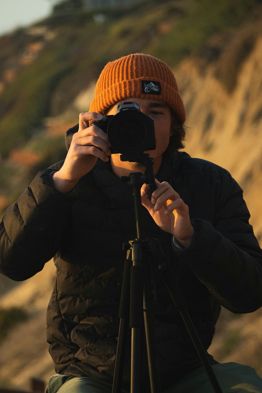 man in black jacket holding black dslr camera