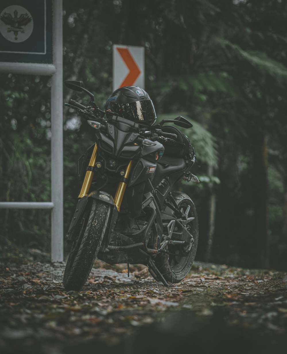 motocicleta preta estacionada ao lado do poste cinza