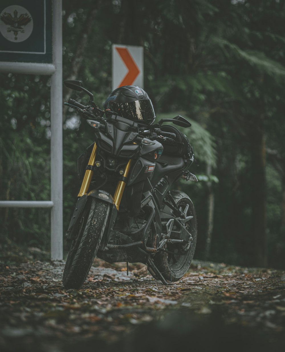 Motocicleta negra estacionada junto a un poste gris