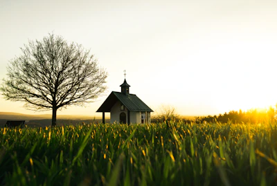 Sunset casting golden light over a rustic western chapel with a simple wooden cross.
