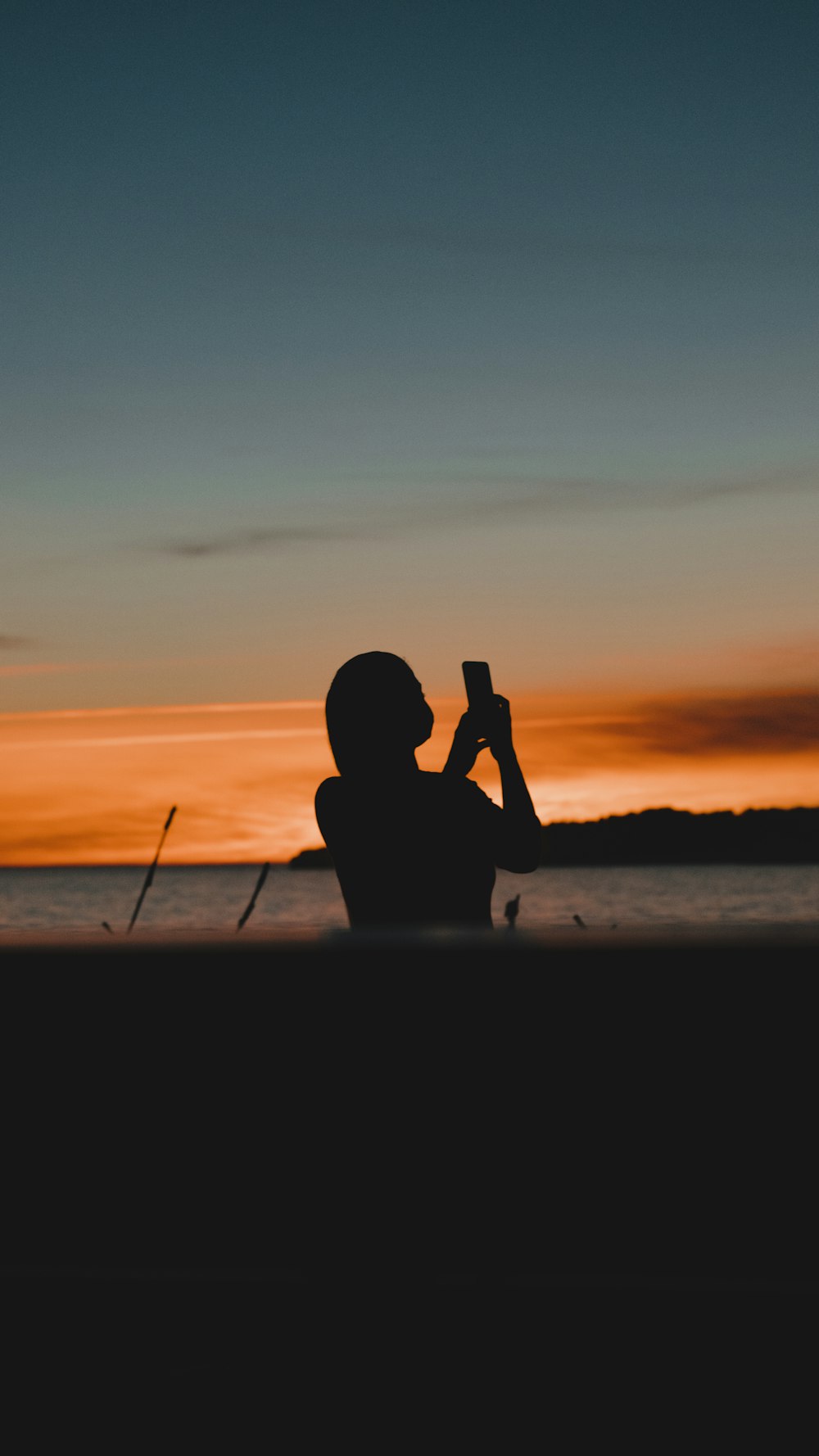 silhouette of man sitting on beach during sunset