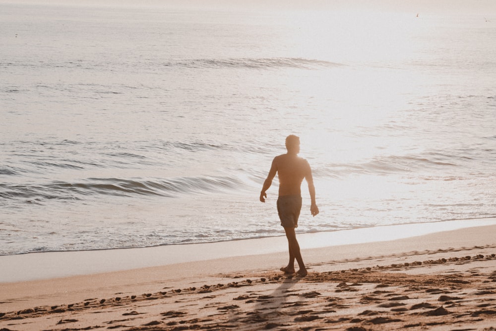 a man walking along a beach next to the ocean