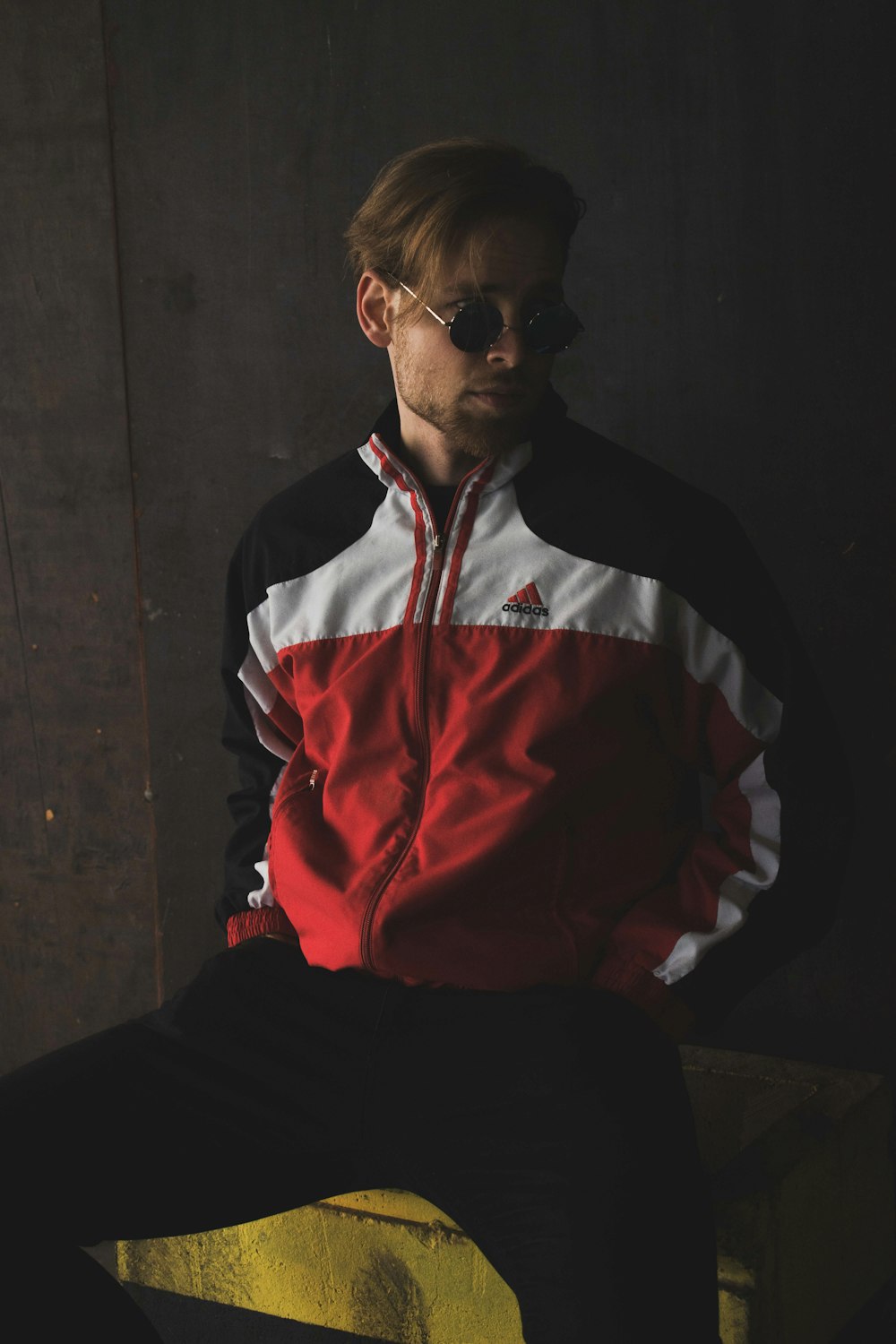 man in red and black jacket and black pants sitting on chair