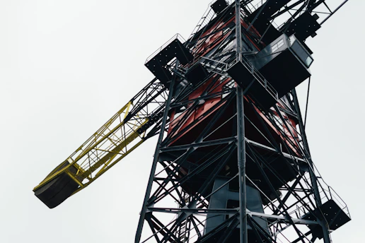 Close-up of a welder reinforcing a crane’s steel frame at an industrial yard.