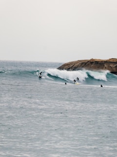 Wide shot of Tamraght’s rocky coastline with surfers paddling out