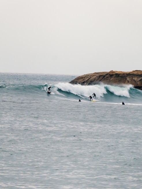 Wide shot of Tamraght’s rocky coastline with surfers paddling out