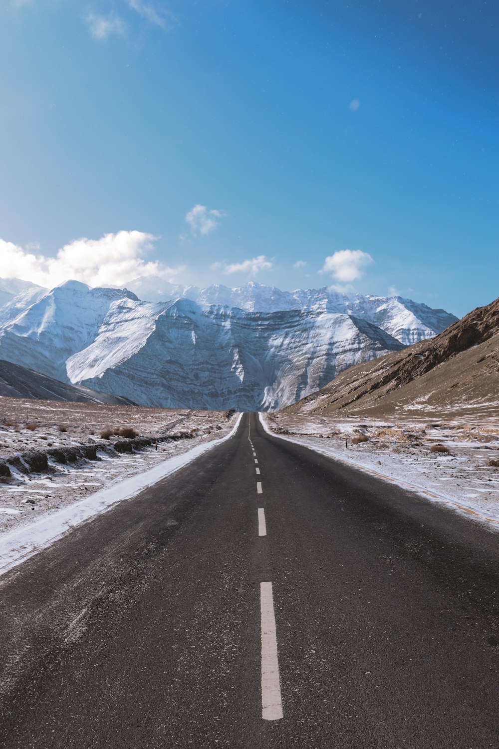 gray concrete road near mountain range under blue sky during daytime