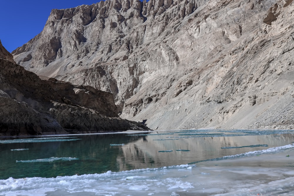 brown rocky mountain beside body of water during daytime