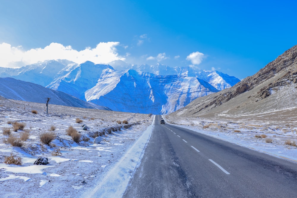 gray concrete road near snow covered mountain during daytime