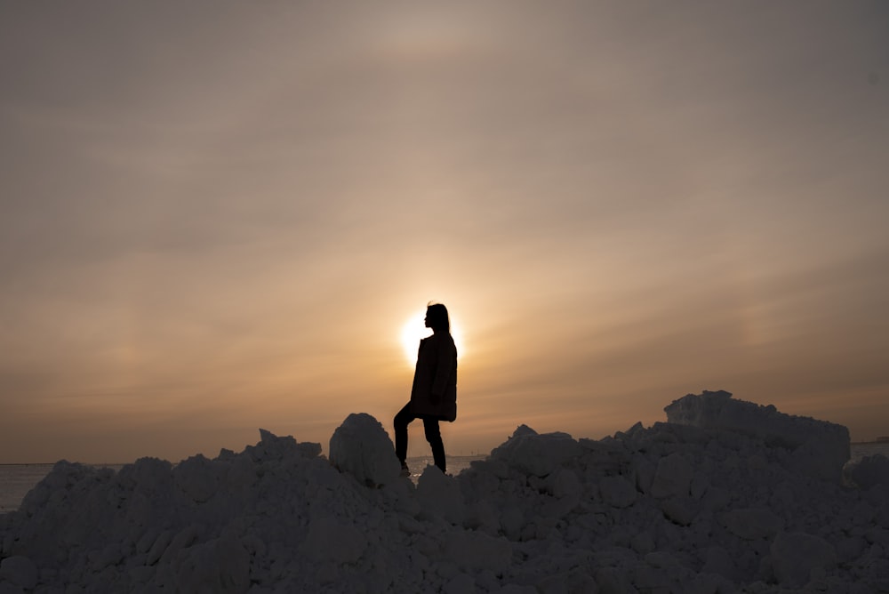 Siluetta della donna in piedi sulla montagna rocciosa durante il tramonto